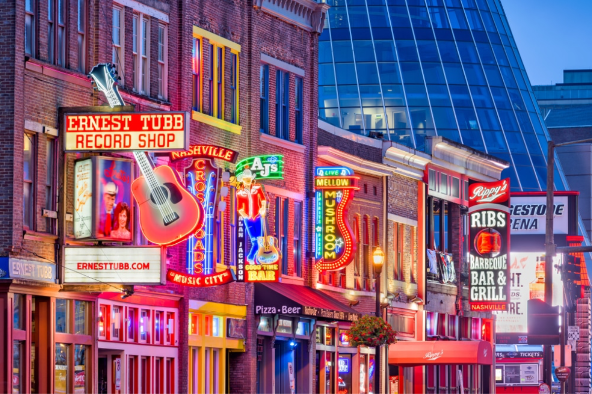downtown nashville's broadway at night time with bright neon signs lining the building